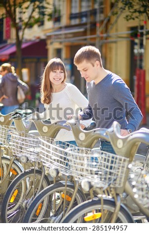Happy romantic couple of tourists taking bikes for rent in Paris on a sunny day. Eco tourism and bicycle tourism concept
