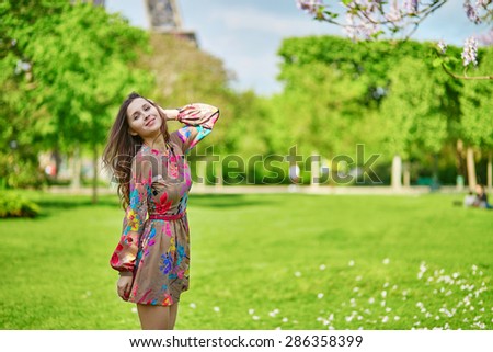 Beautiful young woman walking in Paris near the Eiffel tower on a nice spring or summer day
