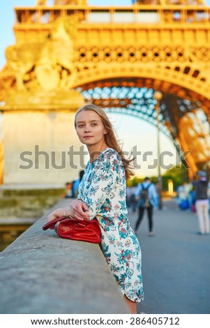 Young beautiful and elegant Parisian woman in blue dress near the Eiffel tower in Paris