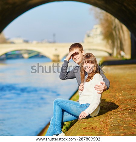 Beautiful romantic couple in Paris walking by the Seine on a nice spring or summer day