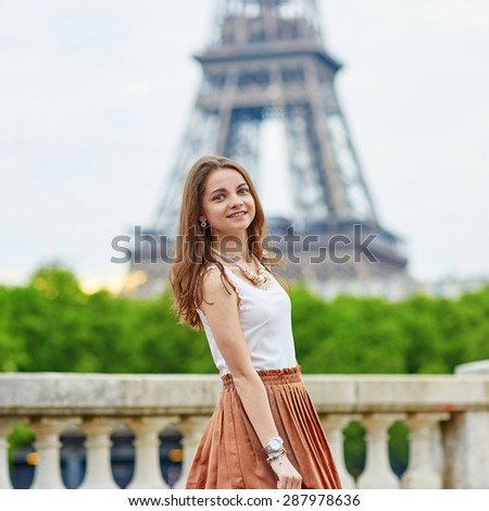 Beautiful young Parisian woman in long skirt near the Eiffel tower on a summer day