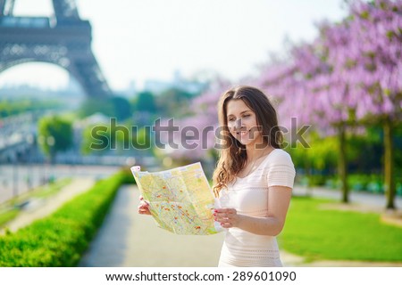 Beautiful young woman on Trocadero view point near the Eiffel tower in Paris, looking at the city map