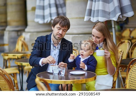 Happy family of three spending time together in an outdoor Parisian cafe
