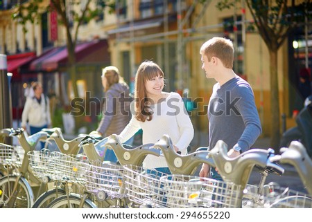 Happy romantic couple of tourists taking bikes for rent in Paris on a sunny day. Eco tourism and bicycle tourism concept