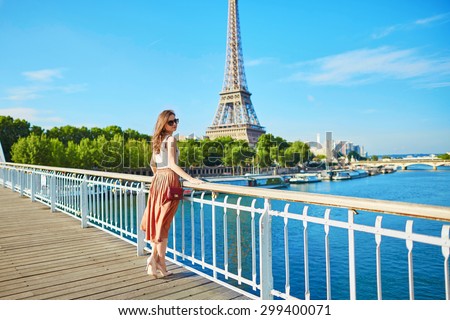 Beautiful young Parisian woman in long skirt near the Eiffel tower on a summer day