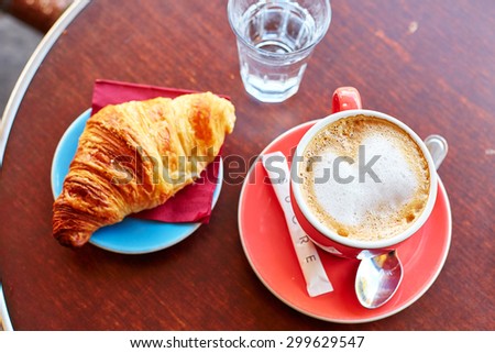 Tasty breakfast in a Parisian street cafe - cup of coffee, croissant and glass of water