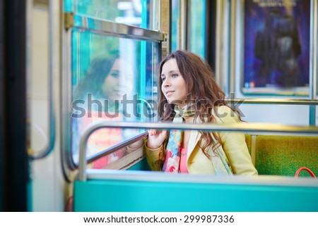 Beautiful young woman travelling in a train of Parisian subway and looking through the window