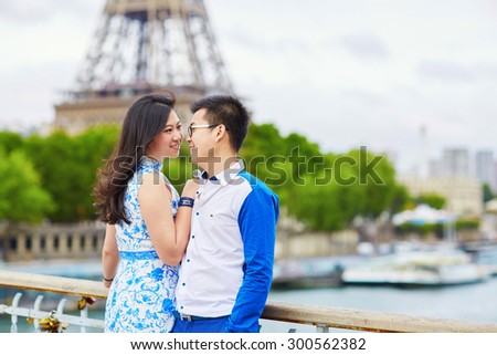 Young romantic Asian couple embracing in front of Eiffel Tower, Paris, France
