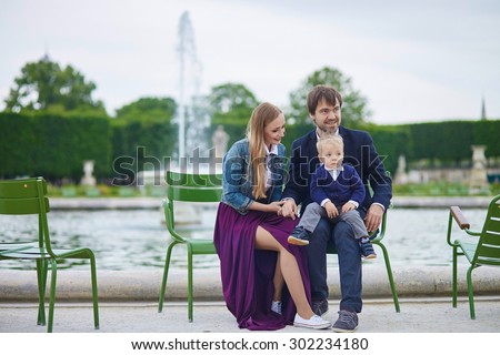 Happy family of three in the beautiful garden of Palais Royal in Paris