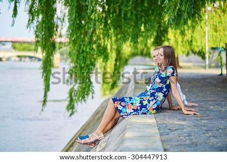 Romantic couple sitting on the Seine embankment on a hot summer day in Paris