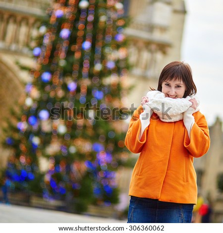 Happy young tourist in Paris on a winter day, main Parisian Christmas tree and Notre-Dame cathedral in the background