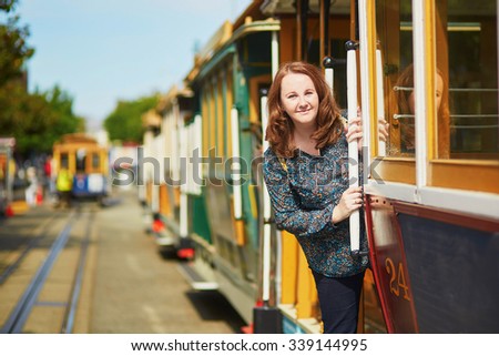 Cheerful tourist taking a ride in famous cable car in San Francisco, California, USA