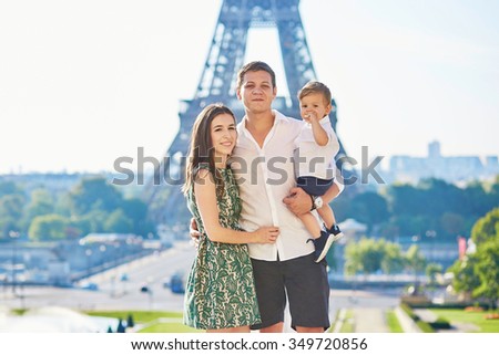 Happy family of three standing in front of the Eiffel tower and enjoying their vacation in Paris, France