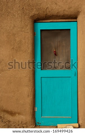Turquoise painted door in Adobe building with chili hanging from door, New Mexico