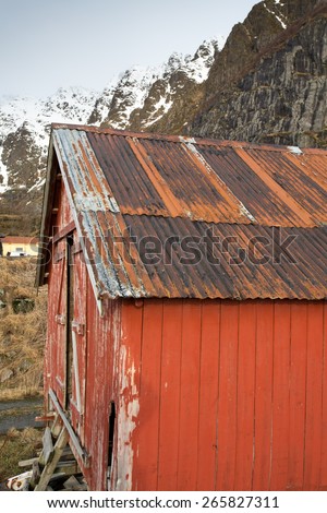 rusted corrugated iron roof of traditional fishing cabin against mountain backdrop, Lofoten, Norway