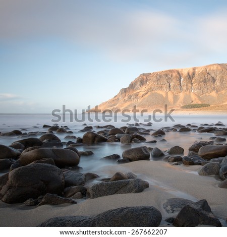 Long exposure showing wave movement around rocks and seaweed on Unstad beach, Lofoten, Norway