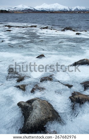 Shards of ice washed up on lake shore like frozen waves, Lofoten, Norway