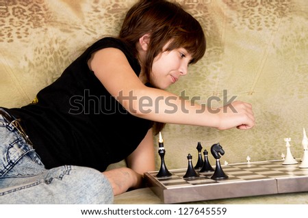 the girl was sitting on the sofa at and plays chess home