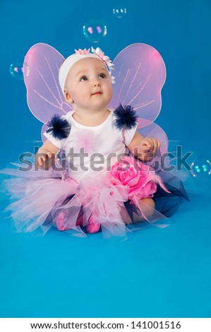 beautiful little fairy on a blue background with soap bubbles