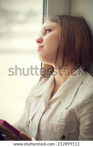 Beautiful girl is sad, sadness due the guy keep picture sit near the window