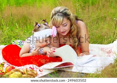Mom with her daughter reading a book on nature