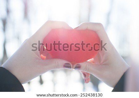 Girl holds and looks on heart in his hand. on the nature