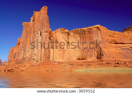 Fantastic background of red cliffs under deep blue sky reflected in rippling water.