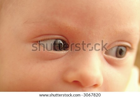 The eyes of infant daughter reflecting loving mother\'s face. Selective focus on the front eye.