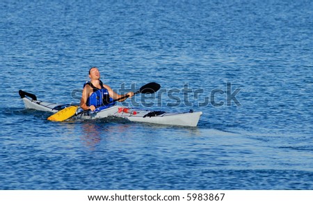 Athletic male kayaker emerges on the surface after paddle float assisted re-entry and roll.