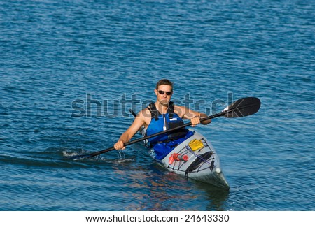 Athletic man showing off his mastery of sea kayak in blue calm waters of Mission Bay, San Diego, California.