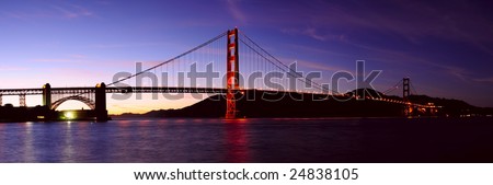 High resolution stitched image of glowing Golden Gate bridge and Fort Point at sunset. First stars can be seen in the sky.