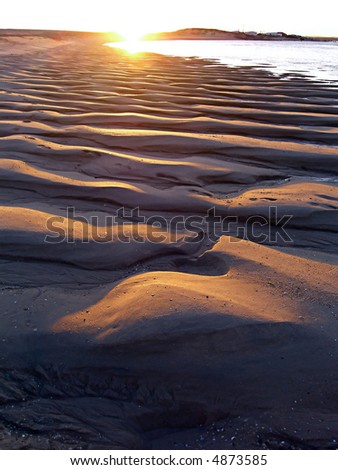 Sand waves on the beach formed by the tide on Faro, Portugal.