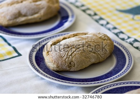 View of three fresh, baked loafs of small breads inside of three plates on top of a table.