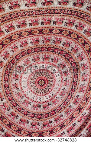 View of a circular redish cloth with islamic designs.