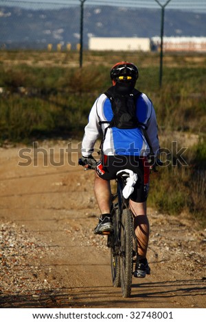 Man wearing sport cloths, riding a bike on the countryside.
