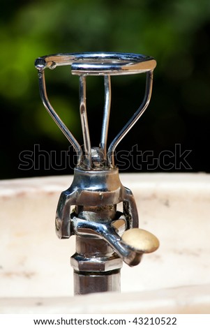 Closeup view of a drinkable public water fountain on a park.