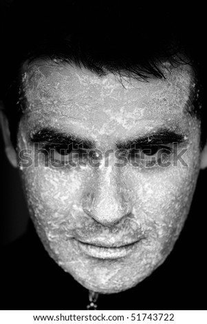Close up view of a man looking at the camera with the face full of flour.
