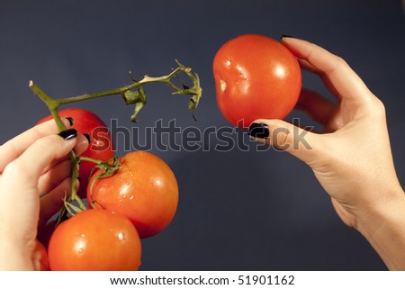 view of a woman hand pulling a red tomato.