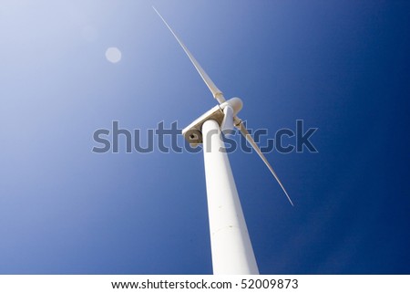 View of a wind generator tower over a blue sky.