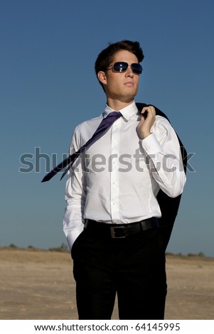 Close up view of a business man in a dark suit walking on the beach.