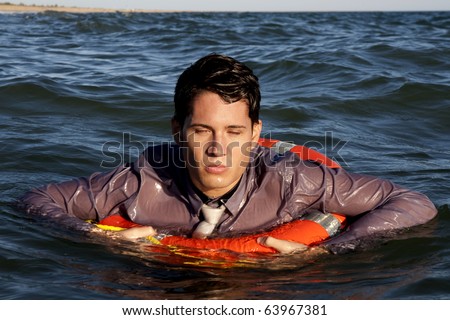 Business man holds a lifesaver buoy on the water.