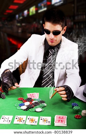 View of a gangster man playing some cards and poker, smoking a Cuban cigar.