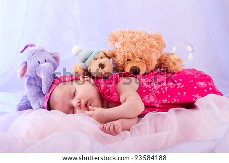 View of a newborn baby on smooth bed with stuffed toy sleeping.