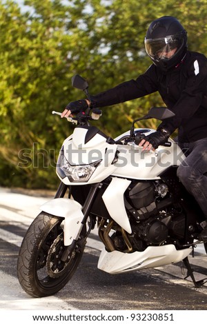 View of a man with a motorcycle on a asphalt road.