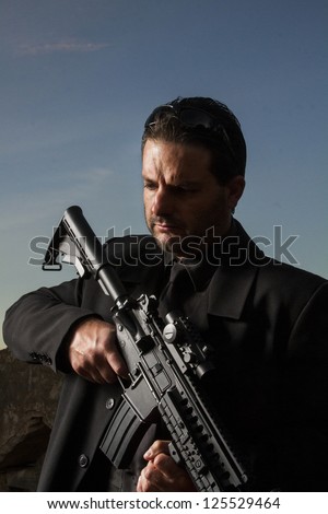View of a contracted type killer agent wandering with a long jacket and machine gun.