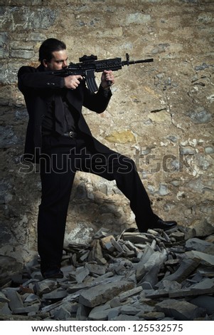 View of a contracted type killer agent wandering with a  jacket and machine gun.