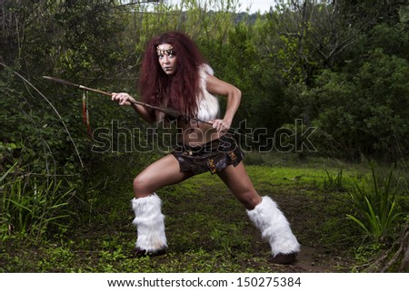 View of a beautiful young strong hunter warrior woman on the forest.