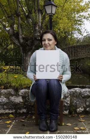View of a beautiful young woman holding a blank canvas on a urban park.