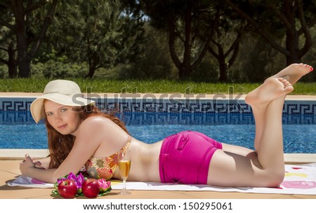 View of a beautiful and happy young woman posing next to a swimming pool.