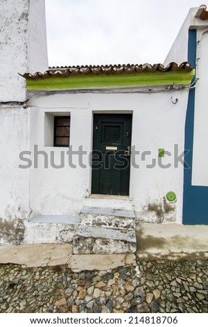 View of a small house in between two bigger houses on a street typical from the region of the Alentejo, Portugal.